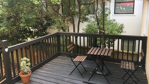 Eine Holzterrasse mit einem roten Sonnenschirm, einem Holztisch und einem Stuhl.