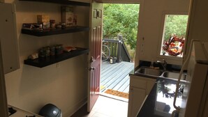 Eine kleine Küche mit einem Gasherd, einem Spülbecken und einem Fenster mit Blick auf eine Terrasse.
