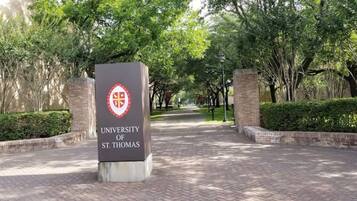 A sign for the University of St. Thomas with a brick pathway leading to it.