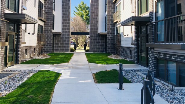 A modern apartment complex with a central walkway, brick facades, and balconies. - Luxury Downtown Traverse City Condo-Capri 2 (Traverse City)