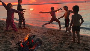 A group of people at a beach with a campfire and a sunset in the background. - Luxury Downtown Traverse City Condo-Capri 2 (Traverse City)