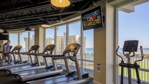A gym with treadmills, a stationary bike, and a TV screen. - TOO BEAUTIFUL GULF and SUNSET VIEWS! (Panama City Beach)
