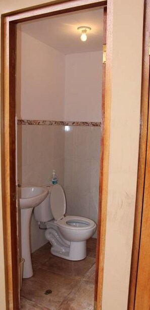 A small bathroom with a toilet, sink, and a bottle of hand soap. - Alpaca Lodge (Chinchero)