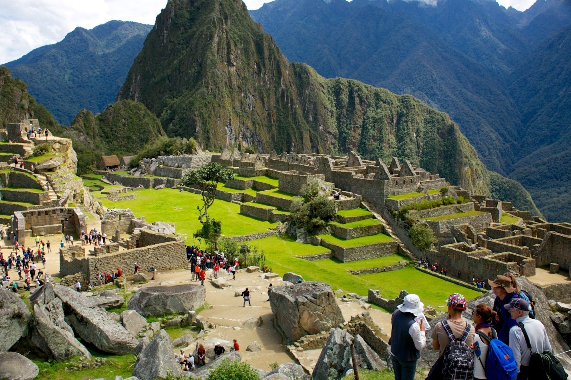 The ruins of Machu Picchu with tourists walking around and a mountain in the background.