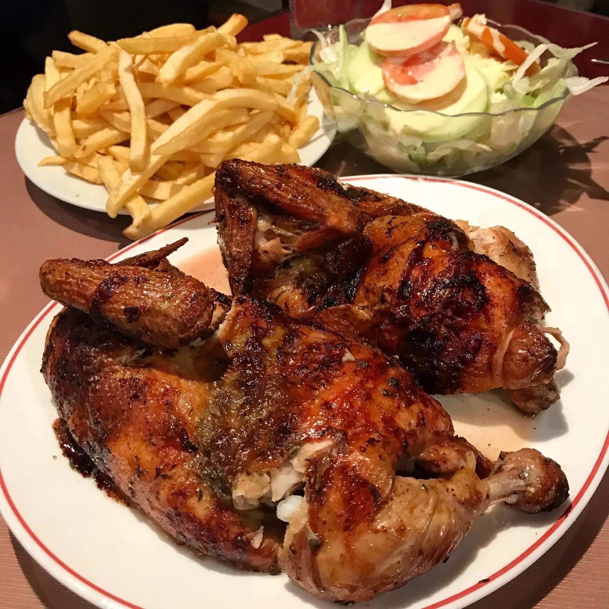 A plate with grilled chicken, French fries, and a salad.