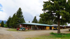 A rustic lodge with a green roof, a covered porch, and a dirt road in front. - Eagle Nest Fly Shack and Lodge (Eagle Nest)