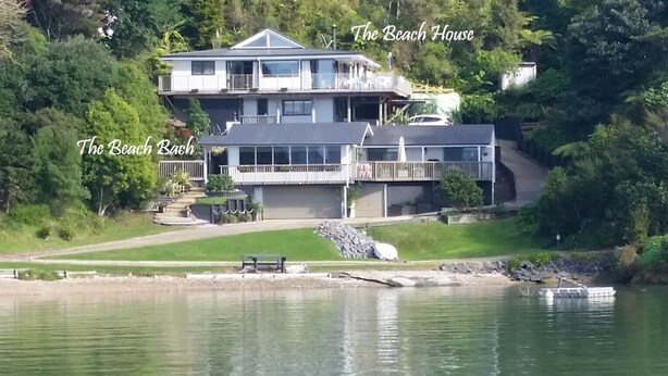 Una casa grande de varios pisos con un balcón, ubicada junto a un lago.