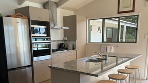 Una cocina moderna con una isla central, electrodomésticos de acero inoxidable y un amplio ventanal.