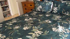 Un dormitorio con cama, cómoda, estantería y espejo.