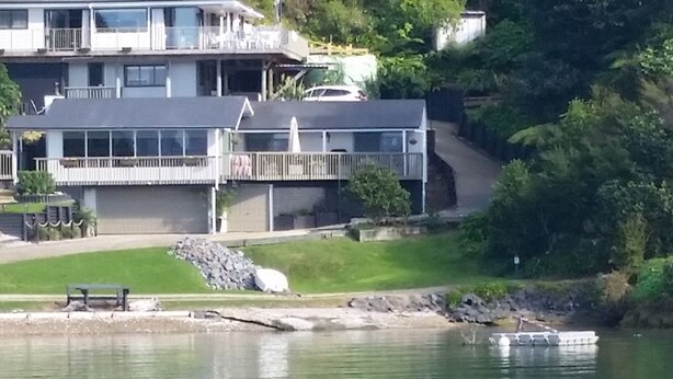 Une grande maison à plusieurs étages, dotée d’un balcon et située au bord d’un lac.