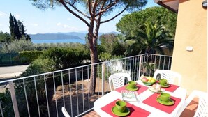 Ein Balkon mit Tisch für zwei Personen, mit Blick auf eine malerische Landschaft mit Bäumen und weiter Wasserfläche.