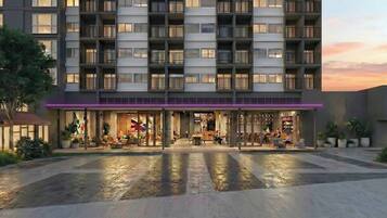 A modern hotel with a ground-level restaurant and outdoor seating.