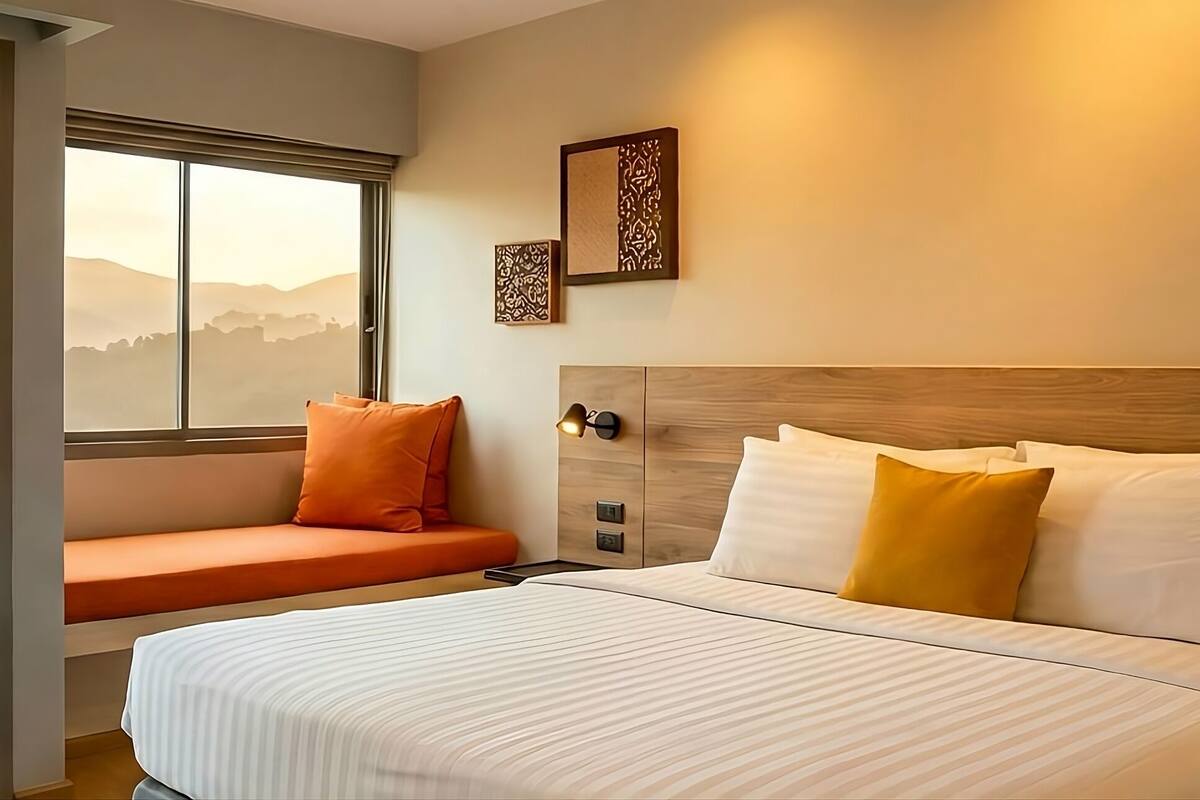 Een hotelkamer met een groot bed, een bank bij het raam en uitzicht op de bergen.