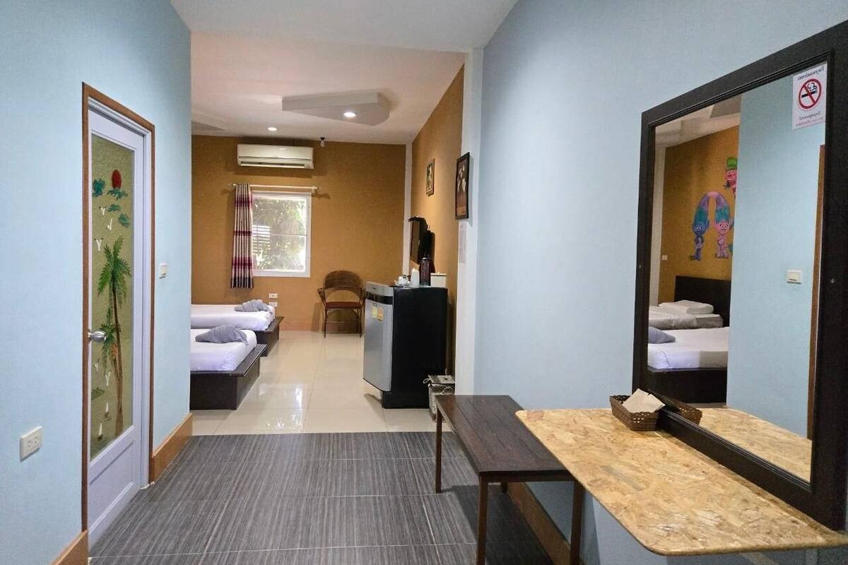 A hotel room with a bed, a desk, a mirror, and a window.