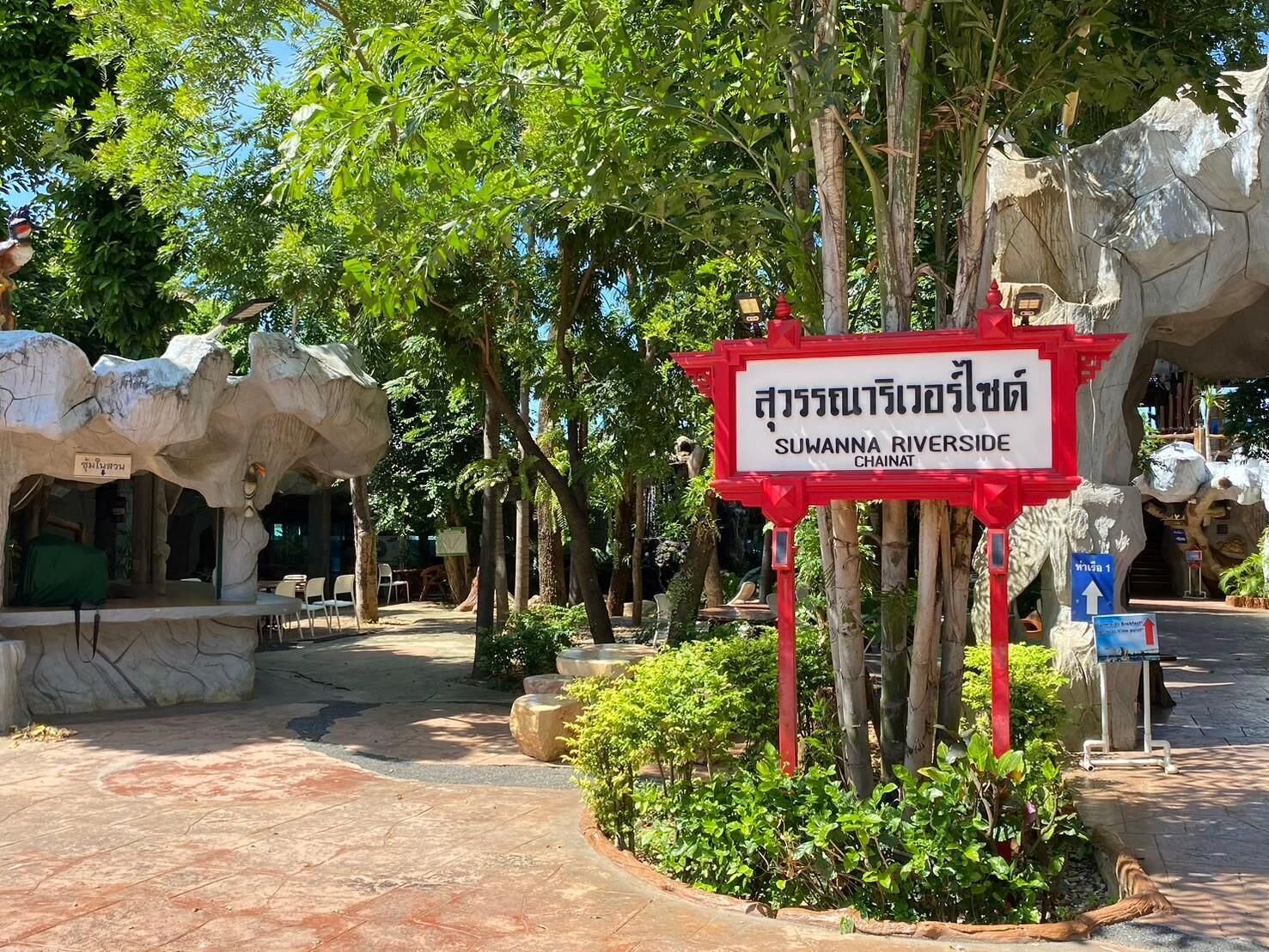 A sign for Suwana Riverside in Chainat, surrounded by rock formations and greenery.
