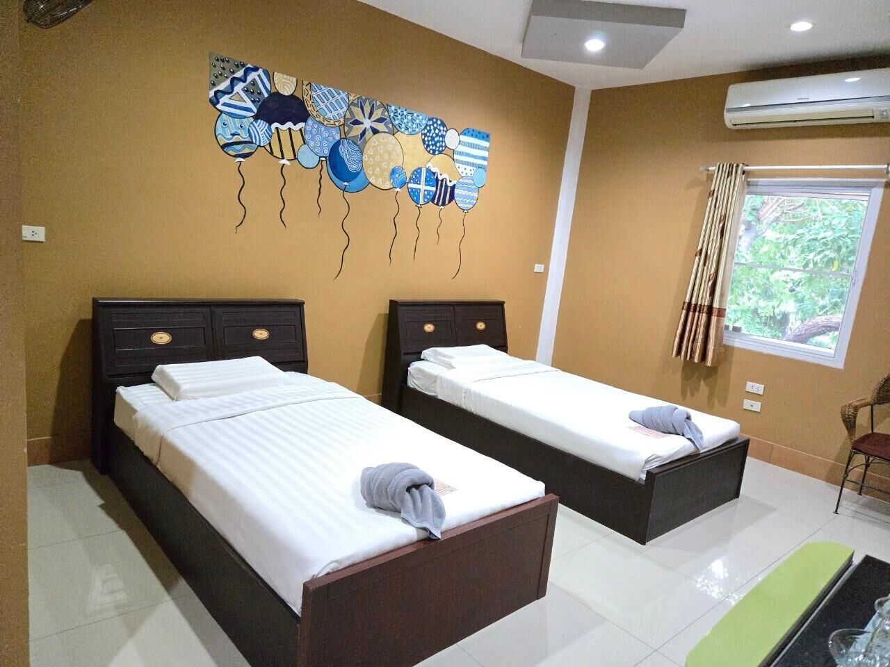 A hotel room with two beds, a wall art piece, an air conditioning unit, and a window with curtains.