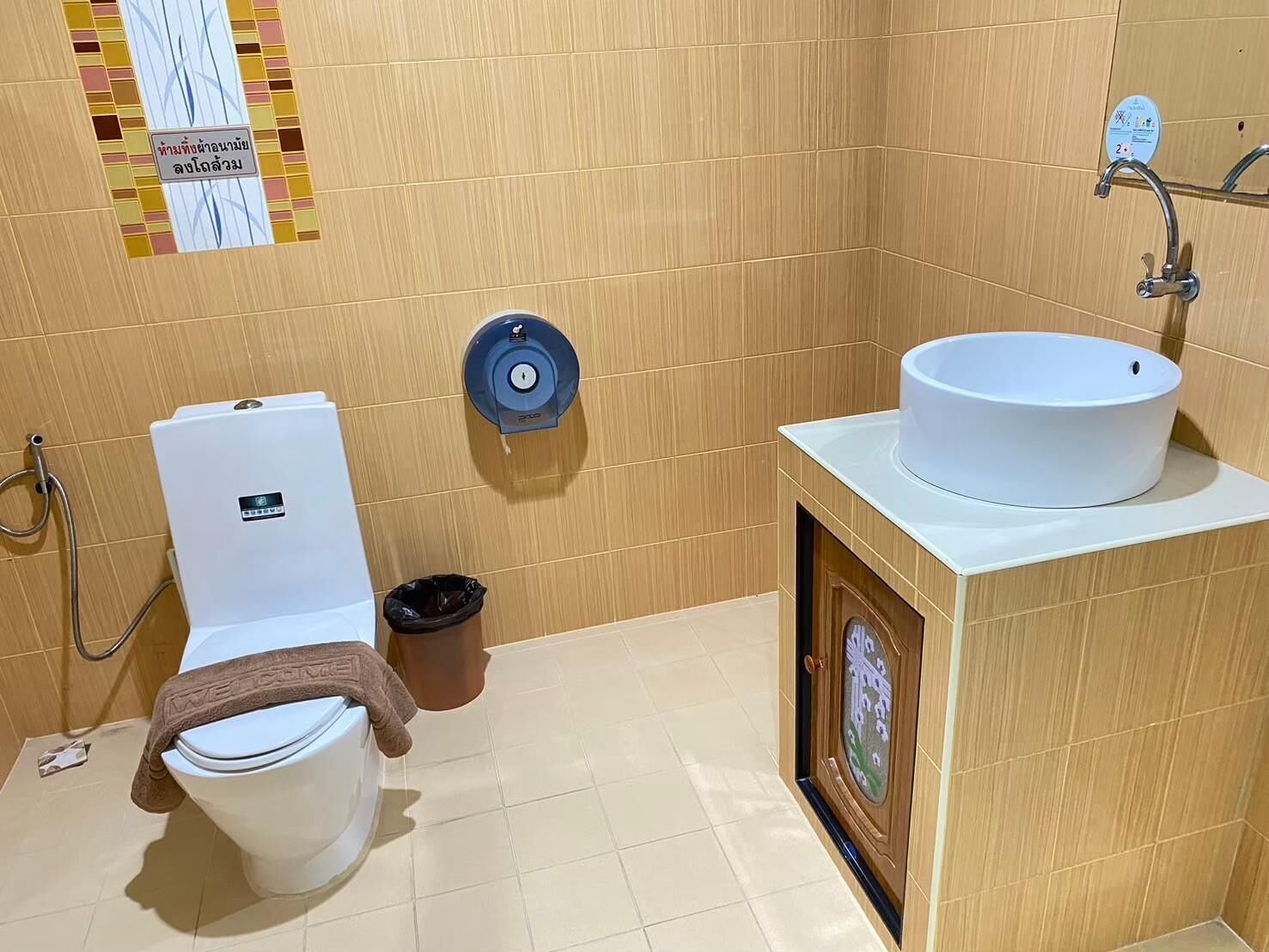 Une salle de bain équipée de toilettes, d’un bidet, d’un lavabo et d’une poubelle.