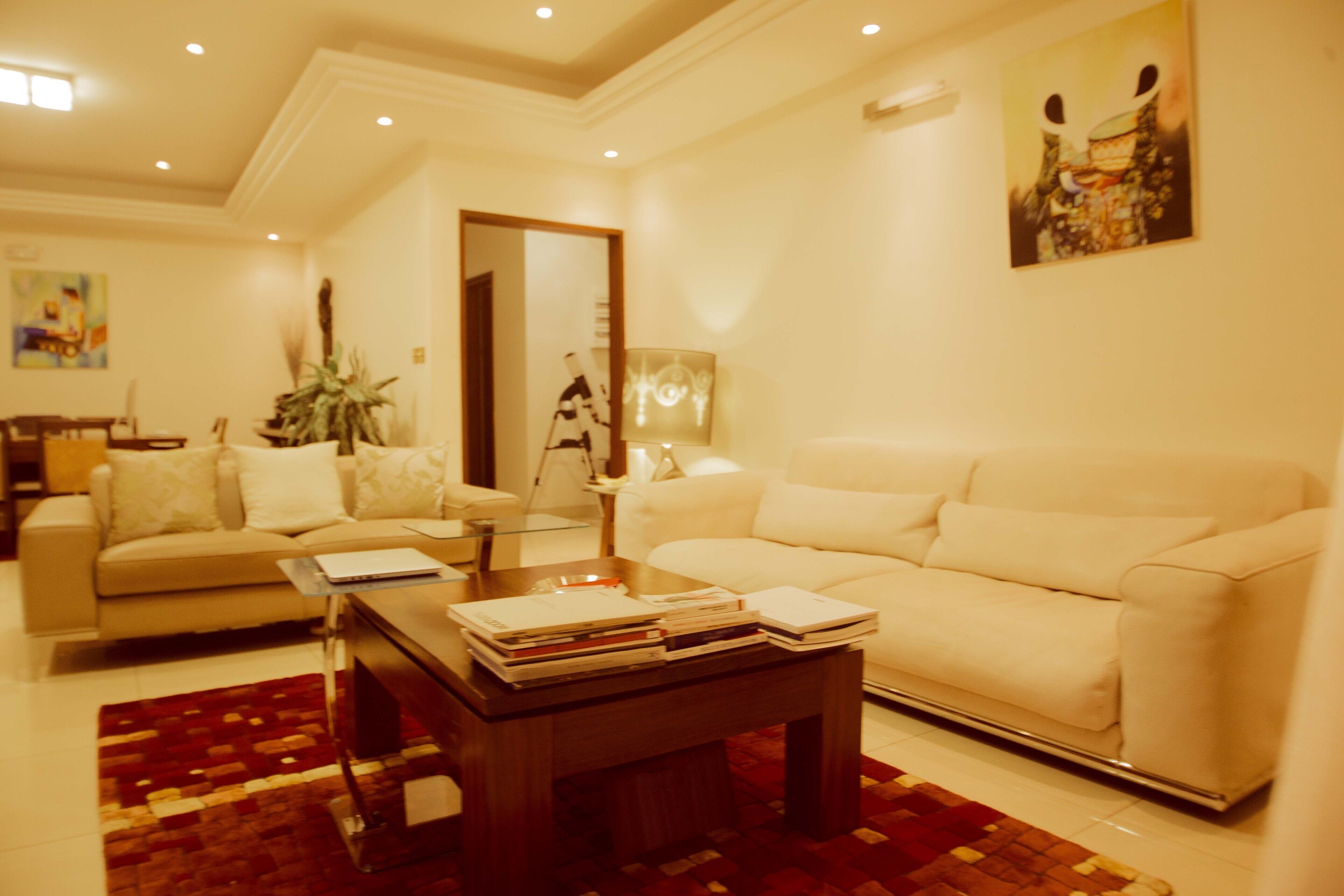 A modern living room with a beige sofa, a coffee table with books, and a patterned rug.