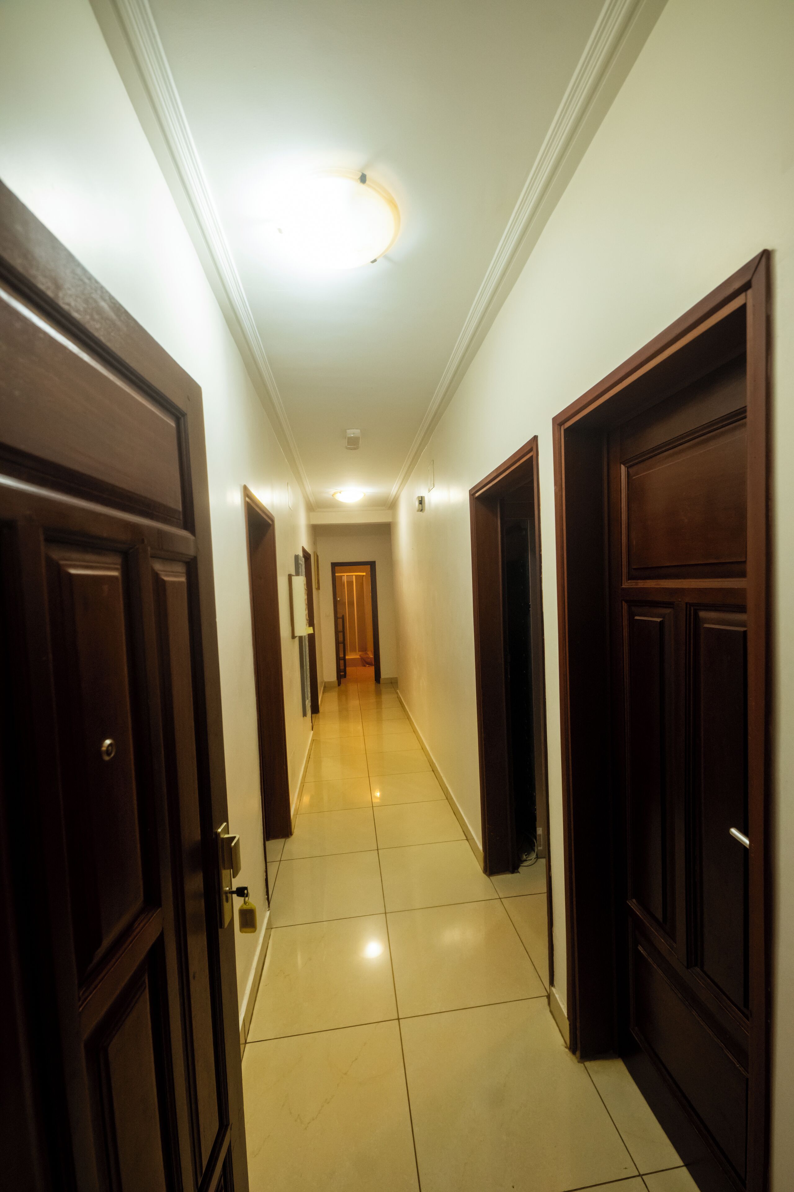 A hallway with wooden doors and a tiled floor.