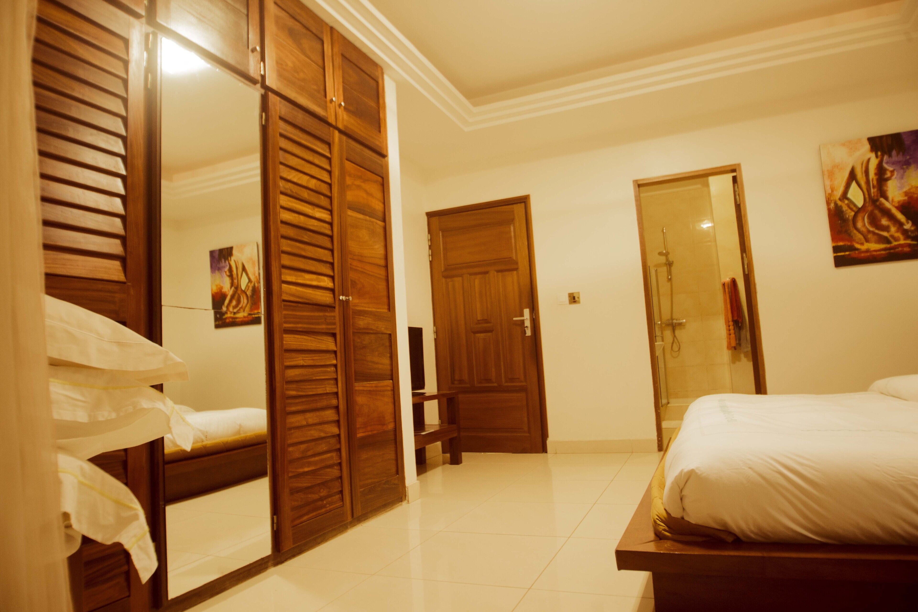 A bedroom with a bed, a wardrobe, a door, and a shower area.