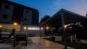 An outdoor patio area with seating and a covered section, illuminated by ambient lighting. - Residence Massou Bastos Golf (Yaoundé)