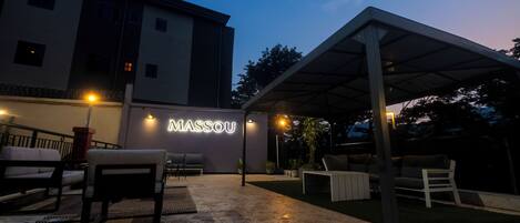 An outdoor patio area with seating and a covered section, illuminated by ambient lighting.