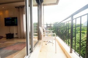 A balcony with a glass door, white chairs, and a TV screen displaying a message. - Residence Massou Bastos Golf (Yaoundé)