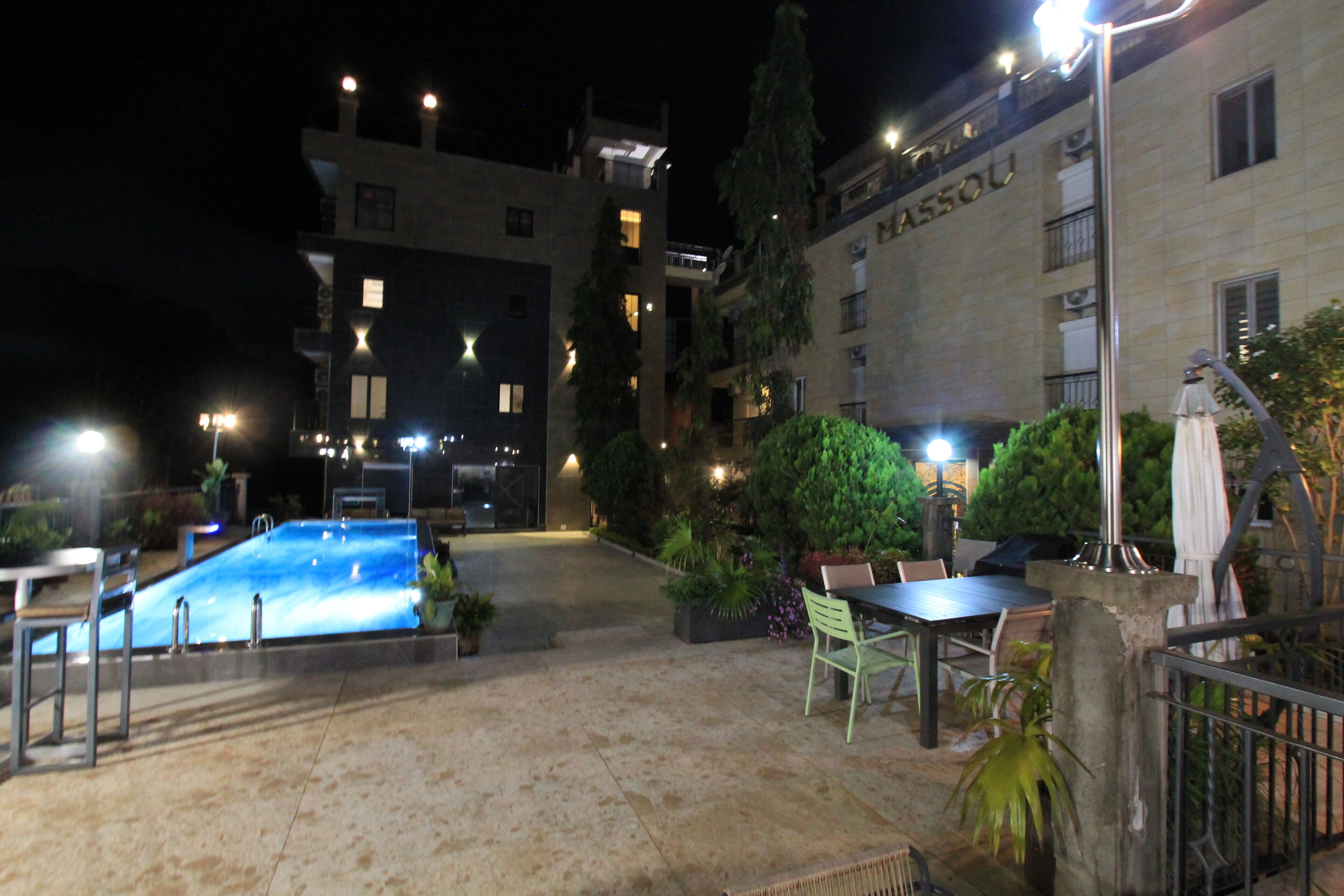 An outdoor pool area with a pool, seating, and potted plants.