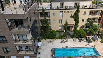 Un edificio de varios pisos con piscina, balcones y zonas de estar al aire libre.