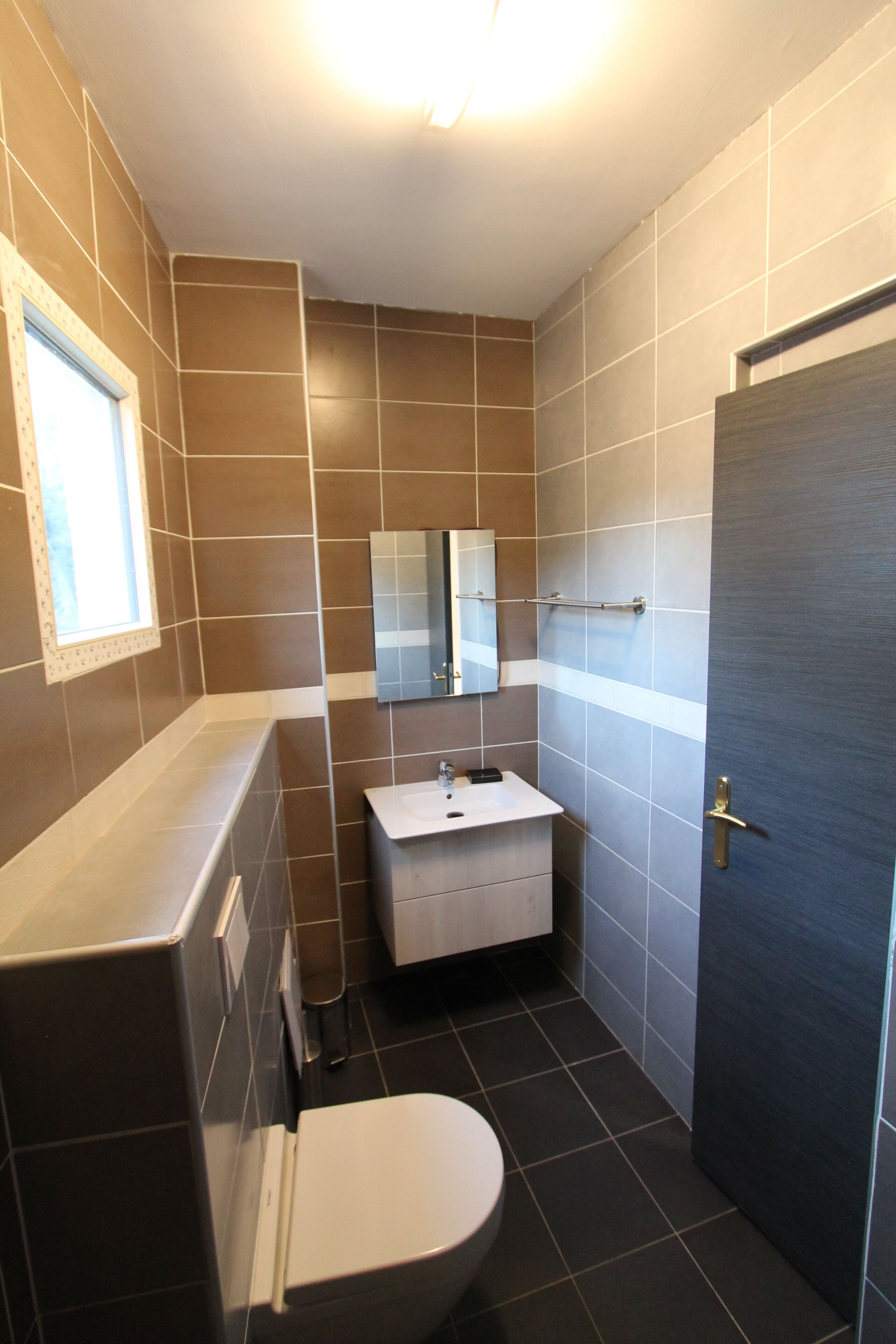 A small bathroom with a toilet, sink, and mirror.