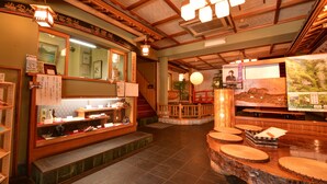 L’intérieur d’un restaurant japonais traditionnel, avec des poutres en bois, un sol recouvert de tatamis et un espace central où sont exposés les différents plats proposés.