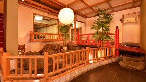 Un intérieur japonais traditionnel avec un plancher en bois, un chemin de pierres et un pont rouge.