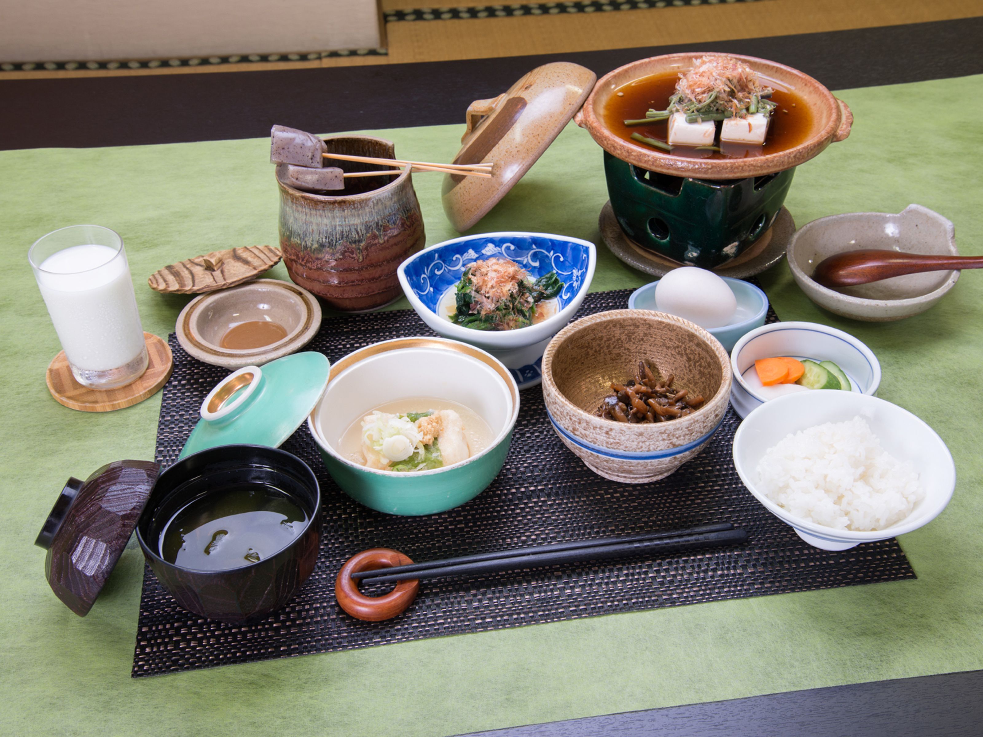 A table with various dishes, including bowls of rice, soup, and vegetables.