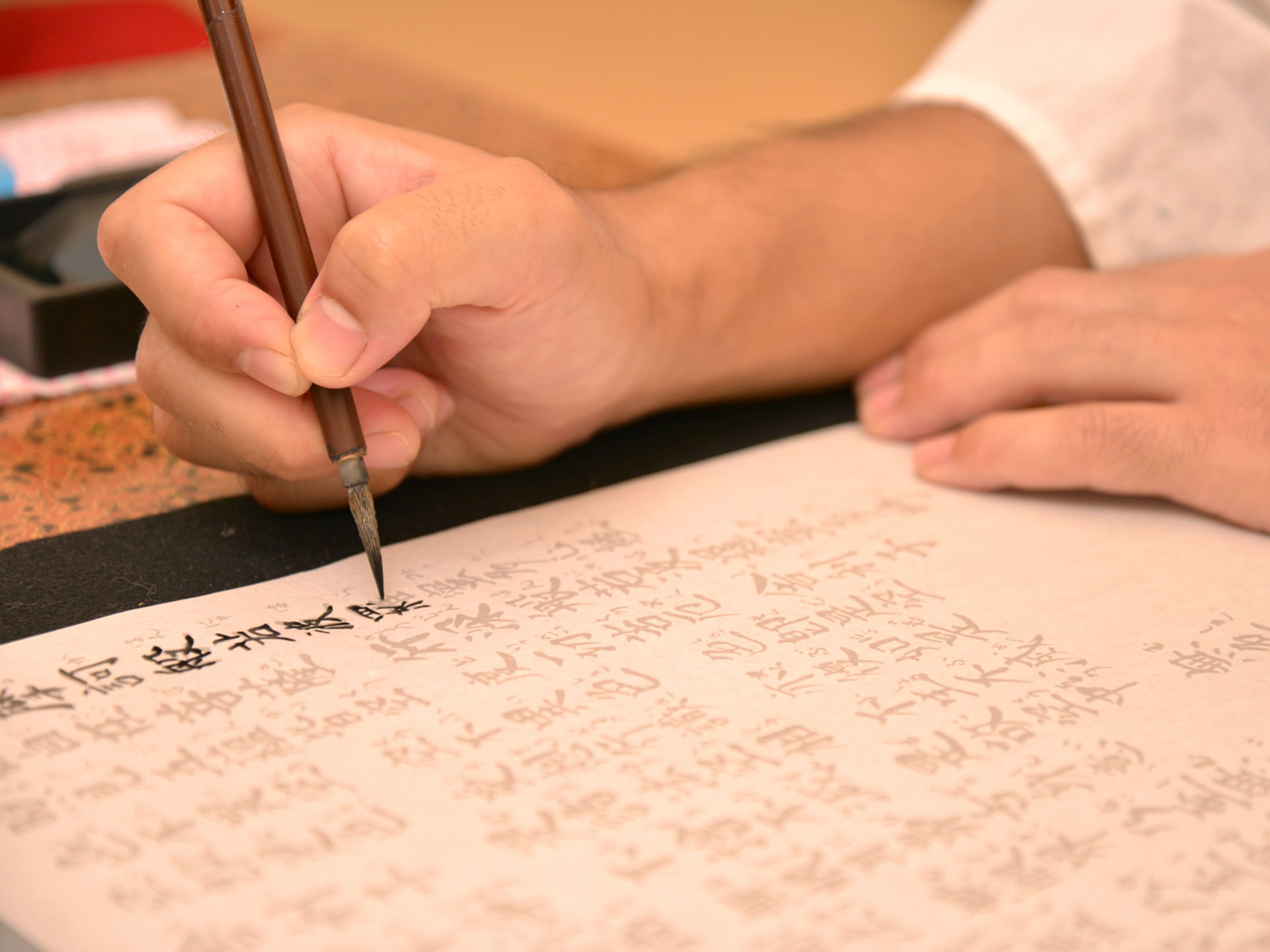 Una persona escribe caracteres chinos sobre un papel con un pincel tradicional.