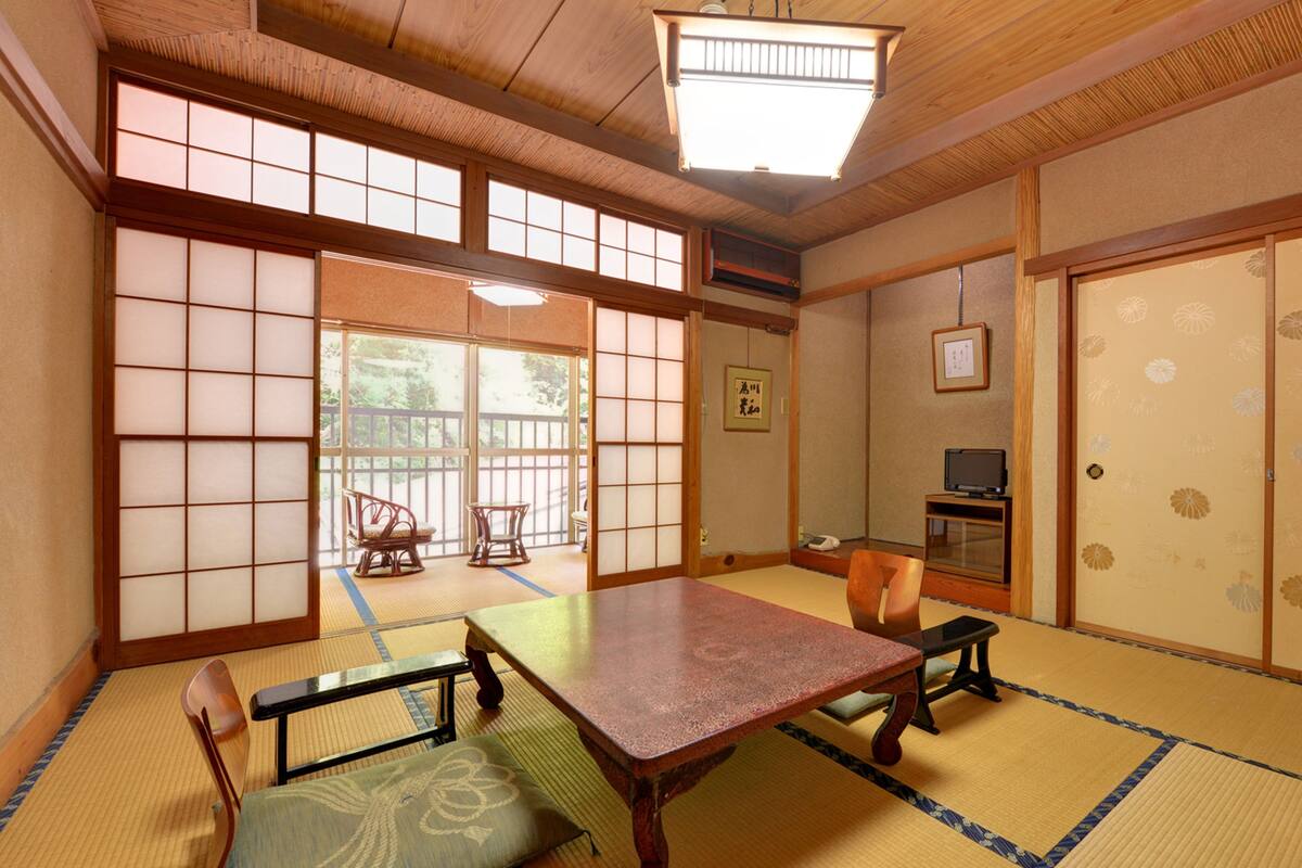 A traditional Japanese room with tatami flooring, a low table, and sliding doors.