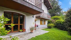 Un bâtiment à deux étages doté d’un balcon, de plantes en pot et d’un chemin de pierre menant à l  ’entrée.