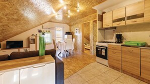 A cozy attic-style room with a dining area, kitchenette, and a TV.