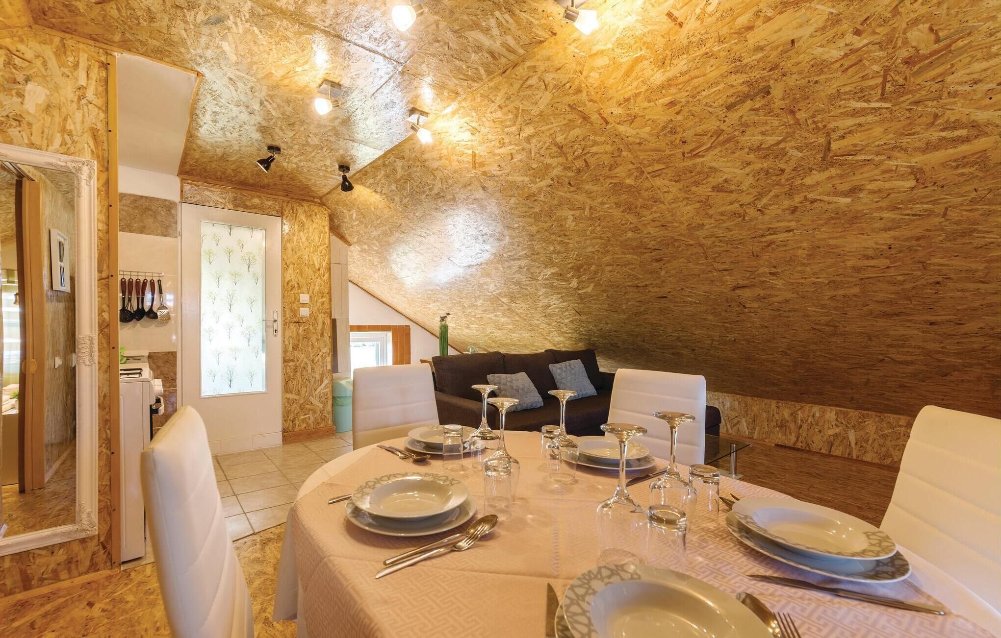 An attic dining room with a high ceiling, wooden beams, and a cozy seating area.