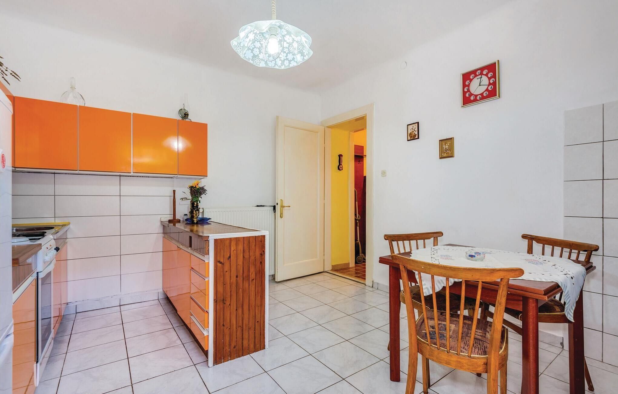 A compact kitchen with orange cabinets, a central island, and a dining area with wooden chairs and a table.