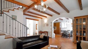 A spacious living room with a black leather sofa, wooden coffee table, and a staircase with wooden beams. - Lovely Stone House with Own Pool in Quiet Village (Tar)