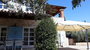 A building with a stone facade, a blue door, and a tiled roof. There are outdoor chairs and a white umbrella. - Lovely Stone House with Own Pool in Quiet Village (Tar)