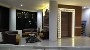 A modern lobby with leather sofas, a coffee table, and a large potted plant. - Hotel Rangkayo Basa Padang Panjang (Padang Panjang)