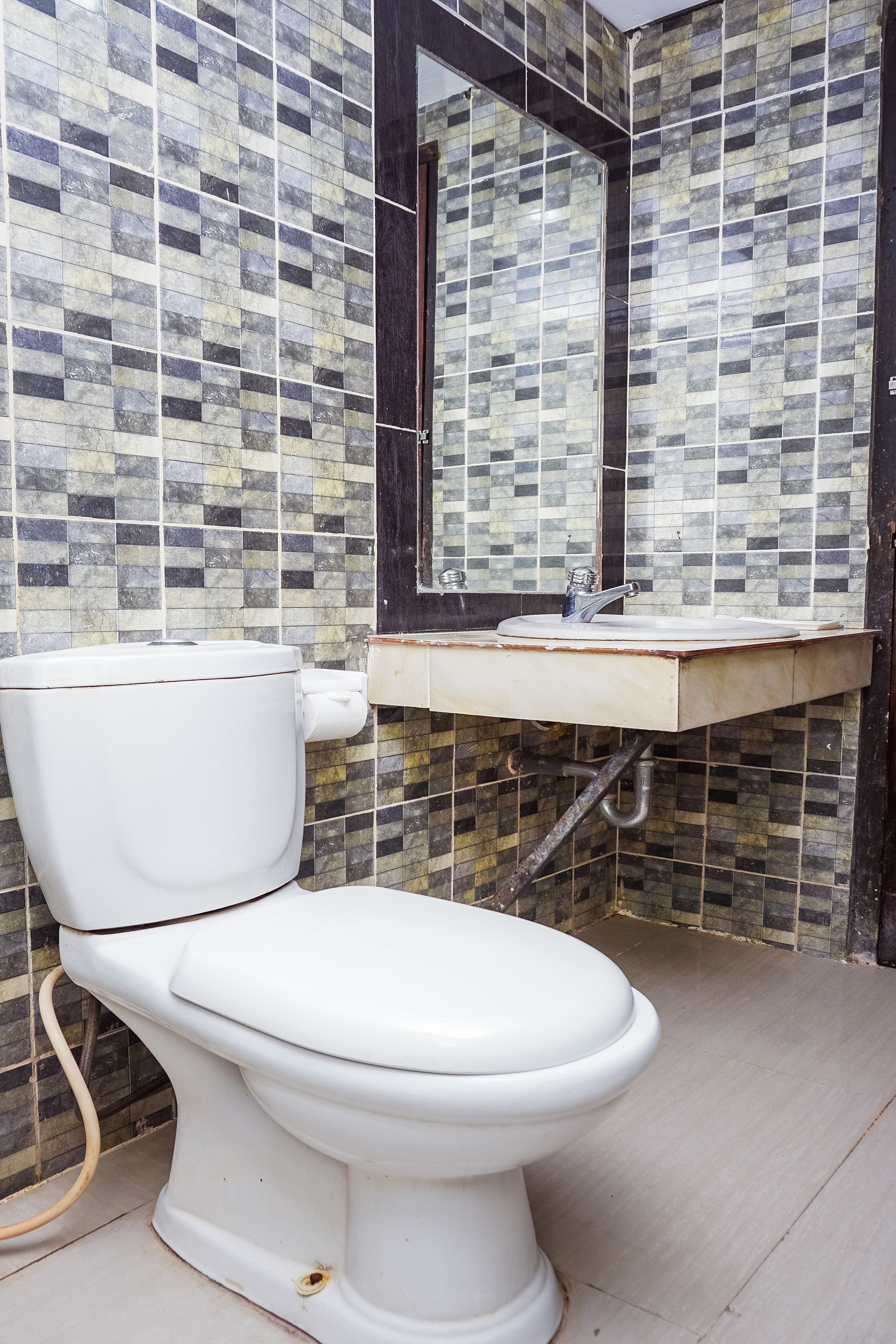 Un baño con inodoro, lavamanos y paredes con azulejos.