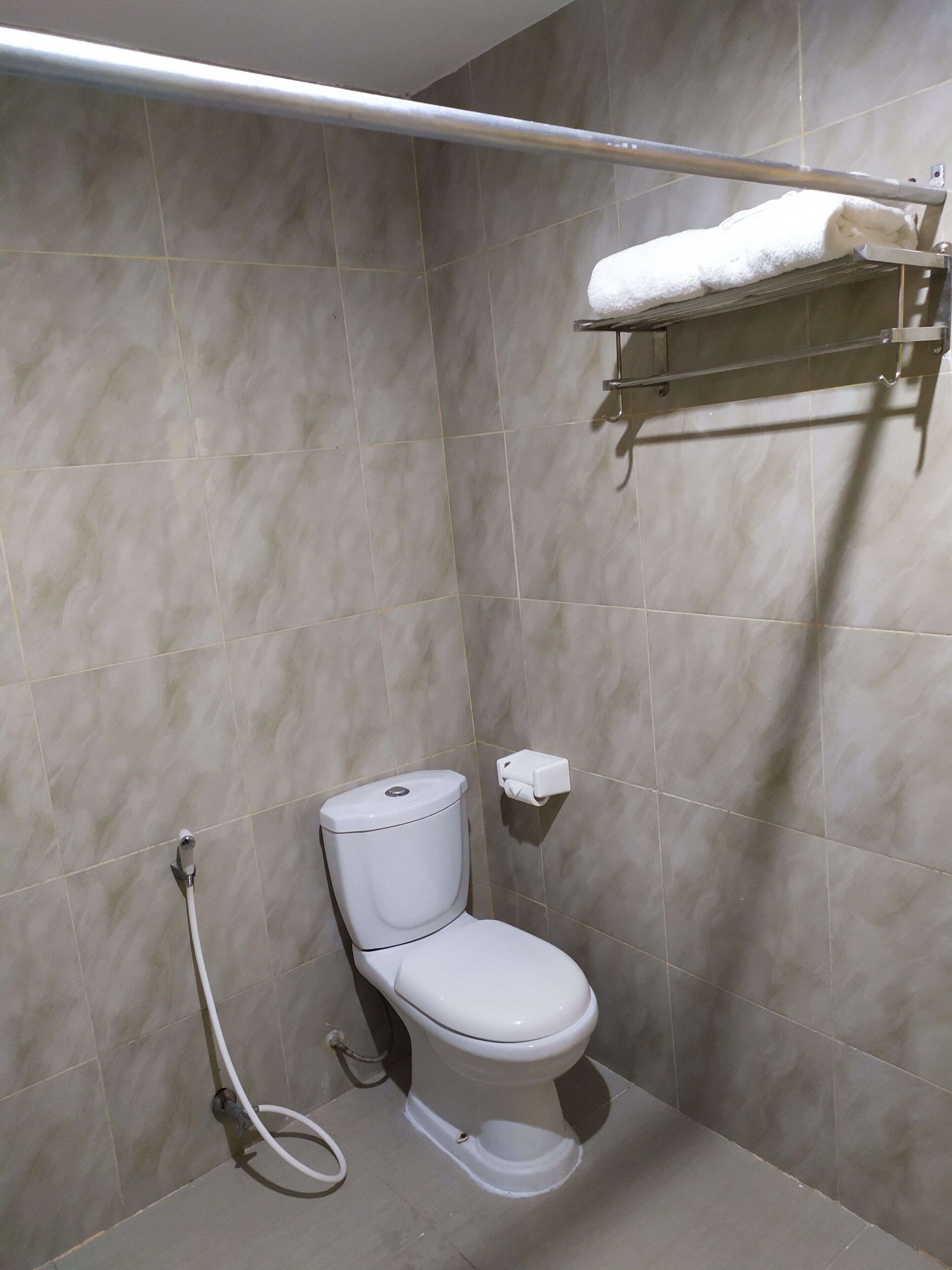 A bathroom with a toilet, a towel rack, and a hand dryer.