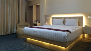 A hotel room with a large bed, bedside tables, a chair, and a wardrobe. - Hotel Rangkayo Basa Padang Panjang (Padang Panjang)
