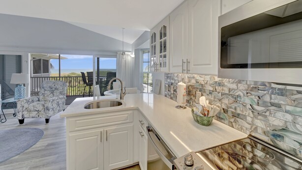 A modern kitchen with white cabinetry, a marble backsplash, and a large island. - Very Nice and Comfortable with a Great View of the Gulf on the Resort, A3724A (Cape Haze)
