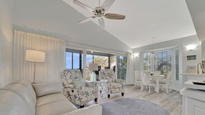 A modern living room with a white sofa, patterned armchairs, a ceiling fan, and a dining area with a table and chairs. - Very Nice and Comfortable with a Great View of the Gulf on the Resort, A3724A (Cape Haze)