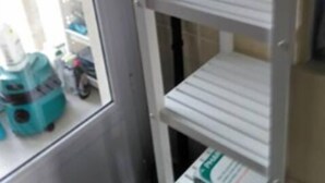 A bathroom with a white sink, a mirror, and a shelf with toiletries.