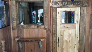 Un intérieur en bois, avec une porte en bois, une petite étagère et un miroir.