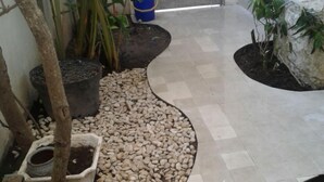 A tiled pathway with pebbles, surrounded by potted plants and a tree. - Kunigen Villa Kuta Bali (Kerobokan)